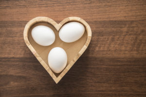 three white eggs lie inside heart deep box