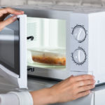 Woman's Hands Closing Microwave Oven Door And Preparing Food At Home