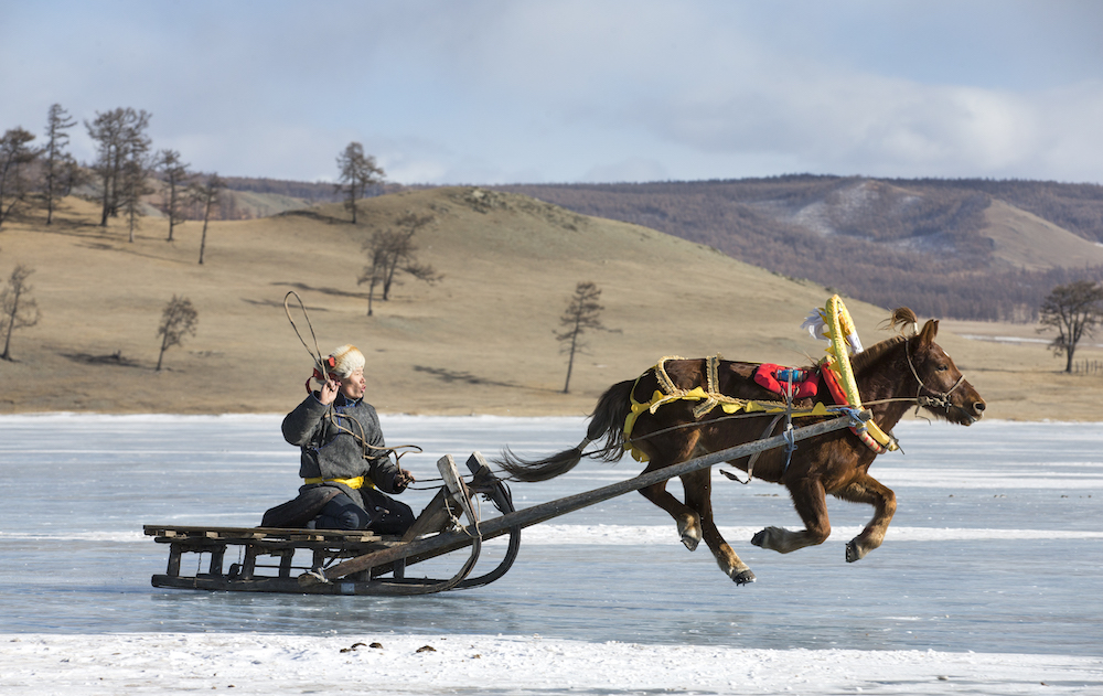Hatgal, Mongolia, 2nd March 2018: people riding on a sledge on a frozen lake Khuvsgul