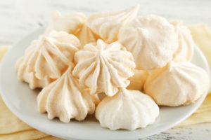 French meringue cookies on plate on white wooden background