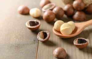 Shelled and unshelled macadamia nuts on old wood background